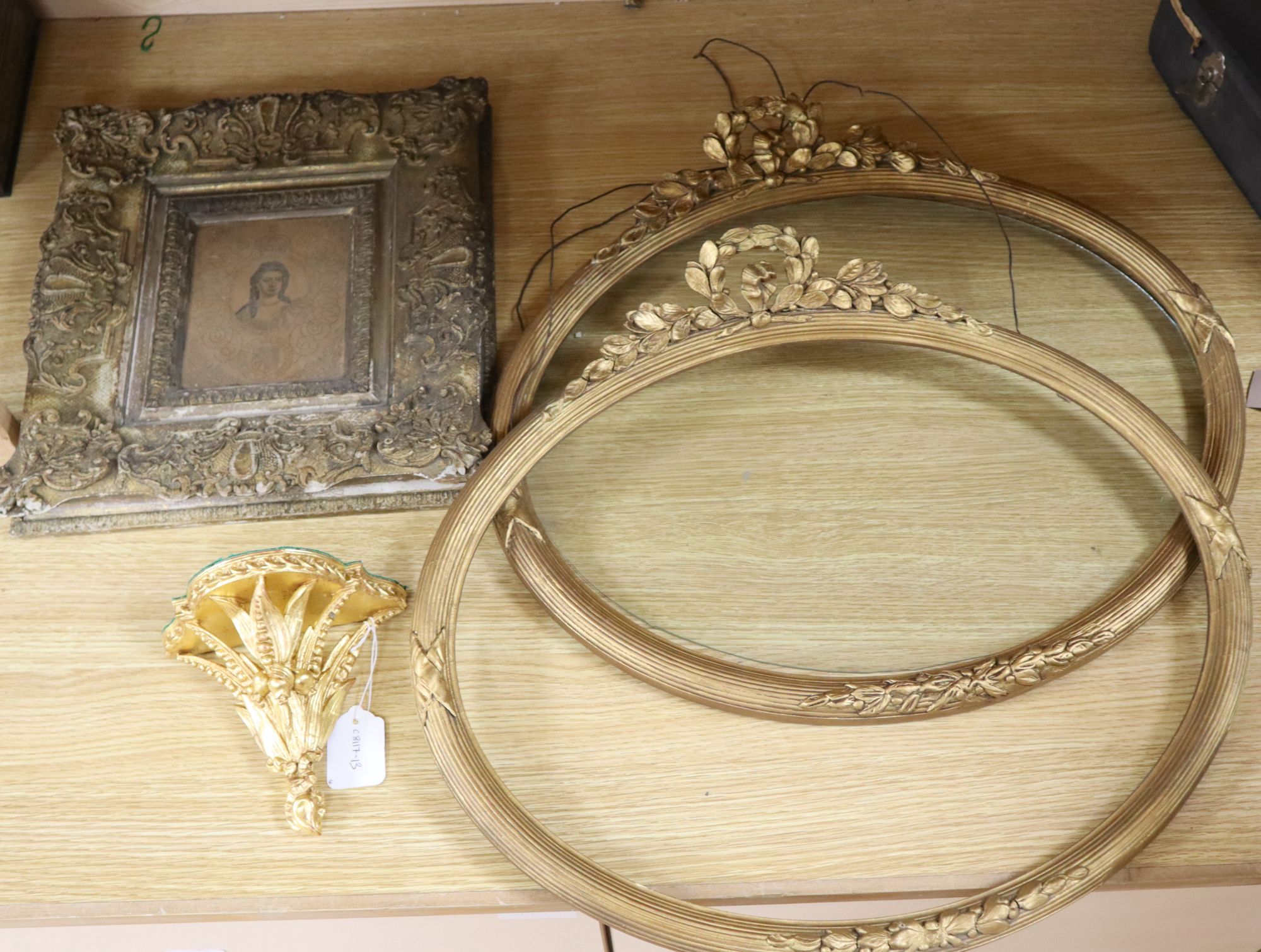 A pair of Victorian ornate gilt gesso oval picture frames, 50 x 55cm, a similar wall shelf and a picture